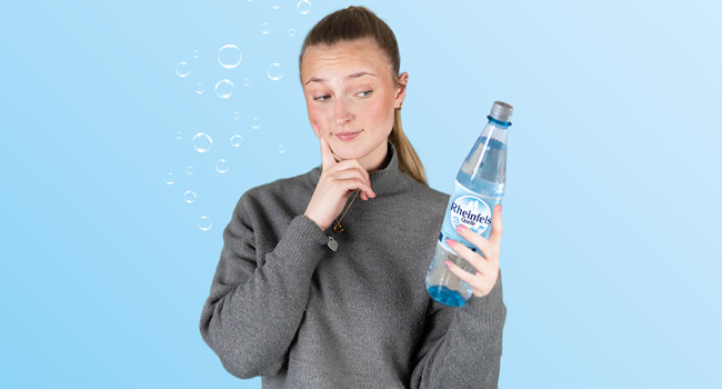 Junge Frau guckt nachdenklich mit Rheinfels Quelle Klassik in der Hand