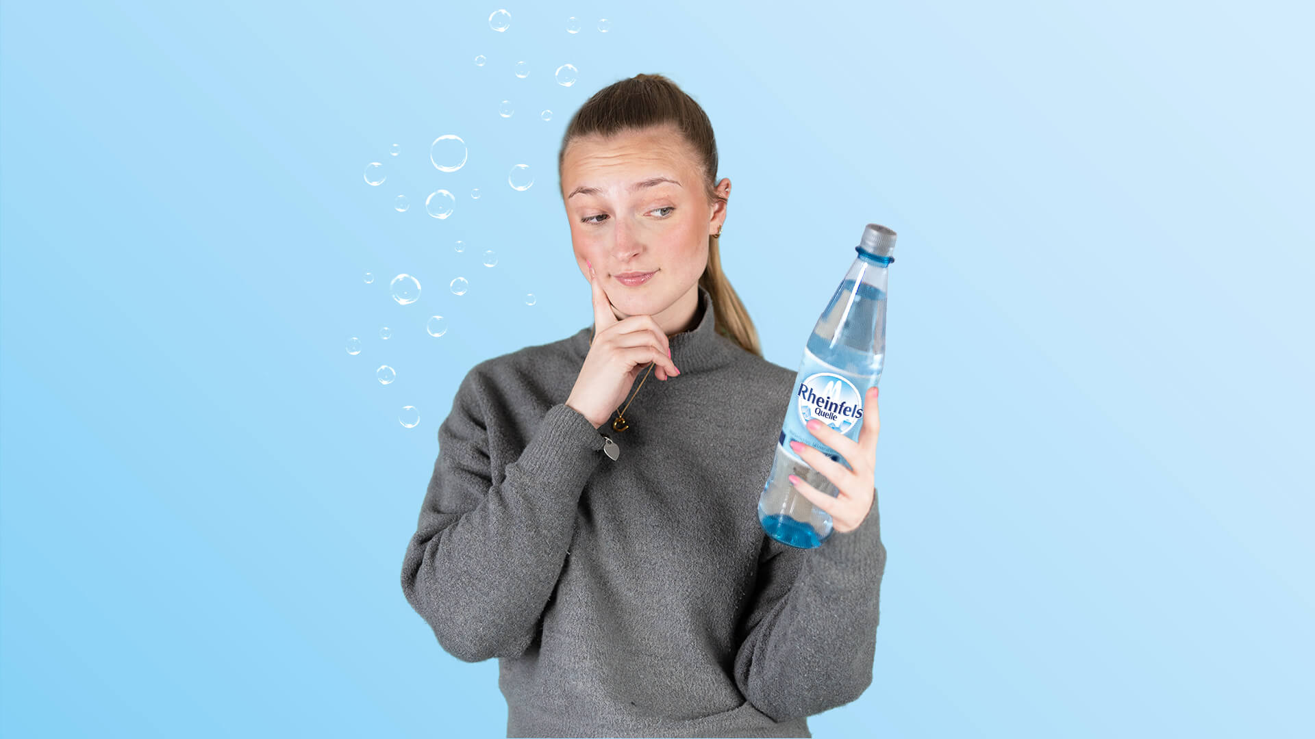 Junge Frau guckt nachdenklich mit Rheinfels Quelle Klassik in der Hand