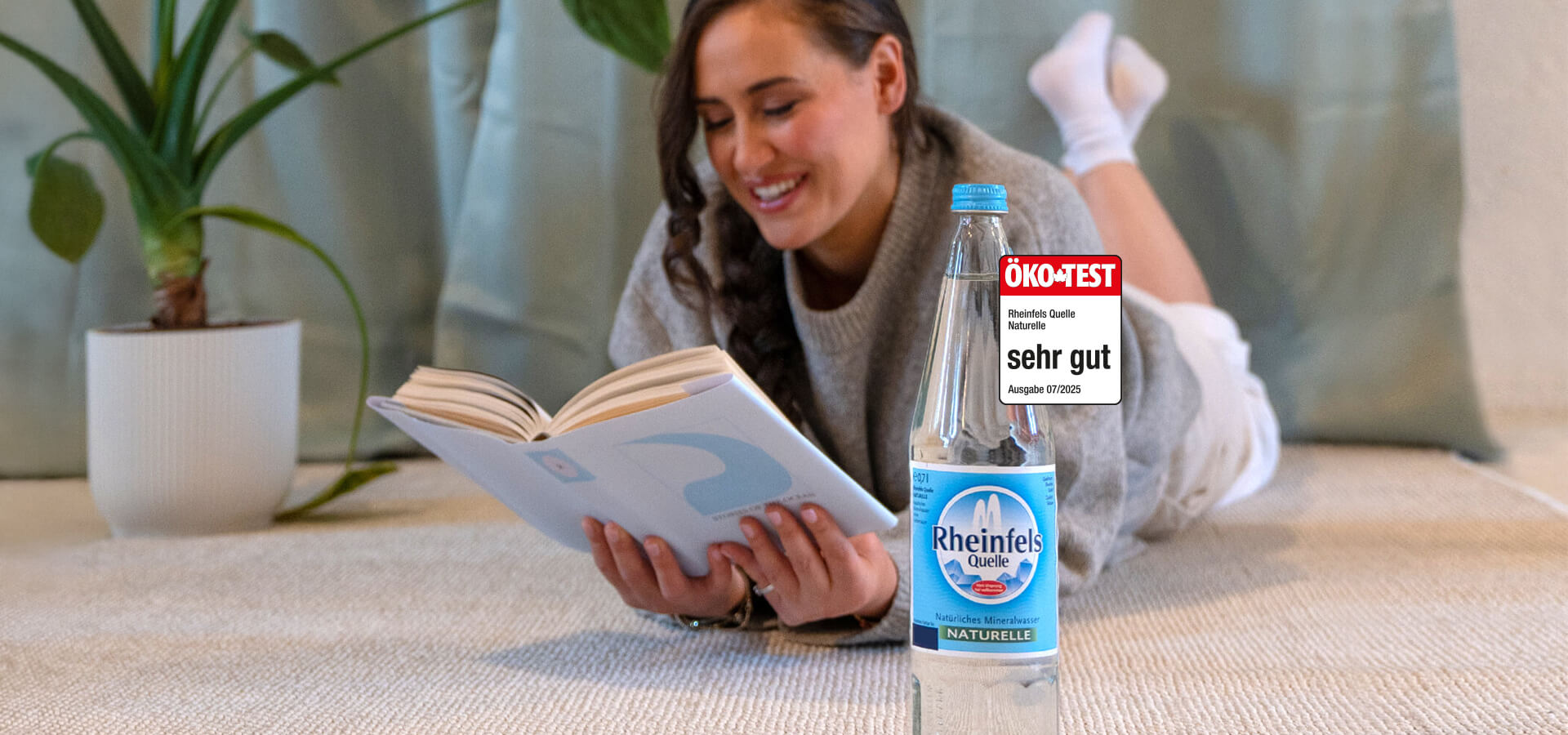 Frau hält Rheinfels Klassik Flasche in der Hand. Daneben ein Ökotest Siegel mit der Note sehr gut