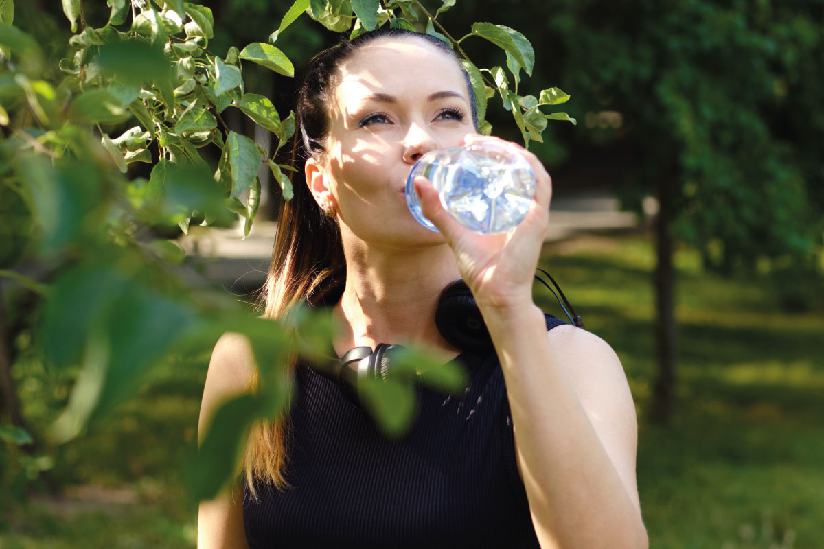 Junge Frau trinkt Rheinfels Quelle auf Wiese