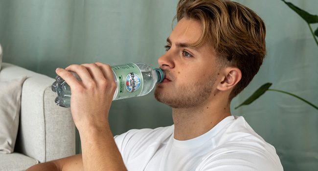 Junger Mann trinkt Rheinfels Medium aus der Flasche