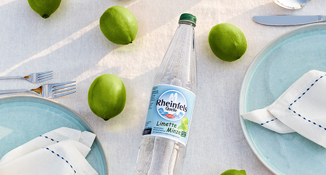 Rheinfels Quelle Limette-Minze Flasche auf gedecktem Tisch.